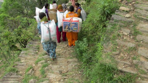 Women carrying bags of rice and flour return to their village